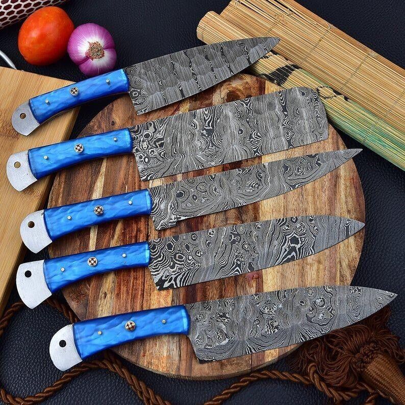 Artisan-crafted Damascus knife kitchen set displayed on a wooden cutting board, showcasing the beautiful blade patterns