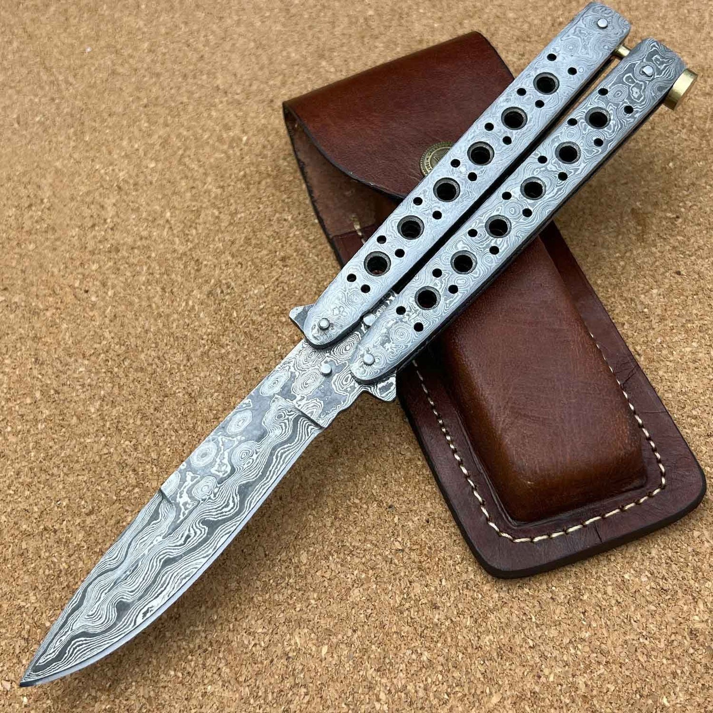 Balisong butterfly knife with Damascus steel blade and premium leather case.