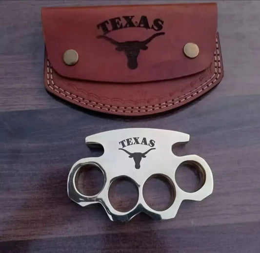 Brass knuckle with engraved design displayed alongside a leather belt loop case