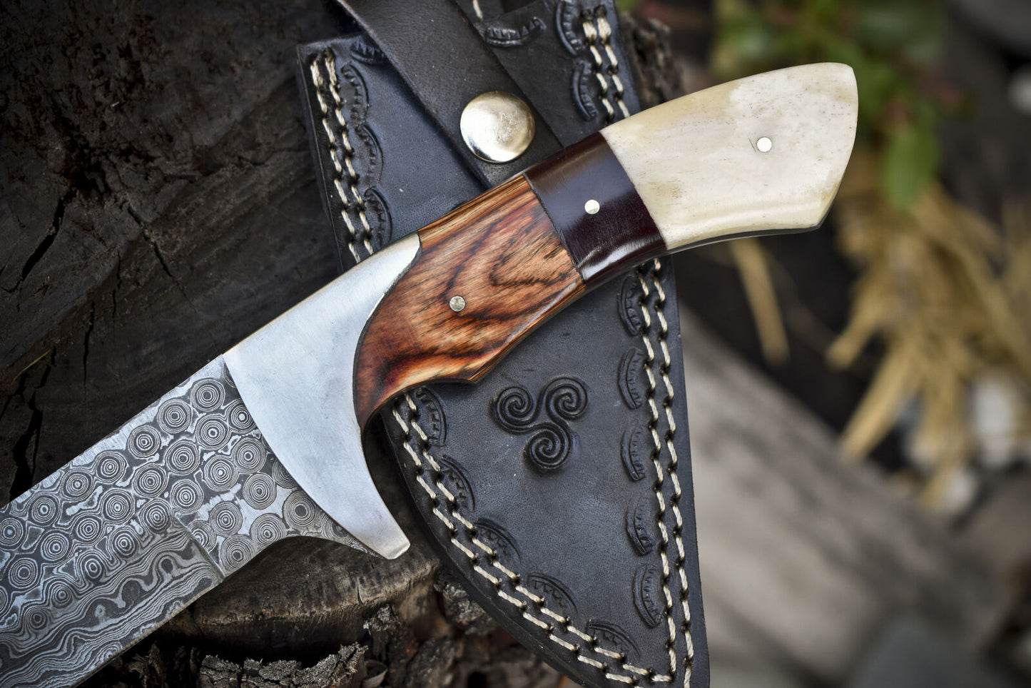 Close-up of Damascus hunting knife with pakkawood and camel bone handle, perfect for outdoor use.