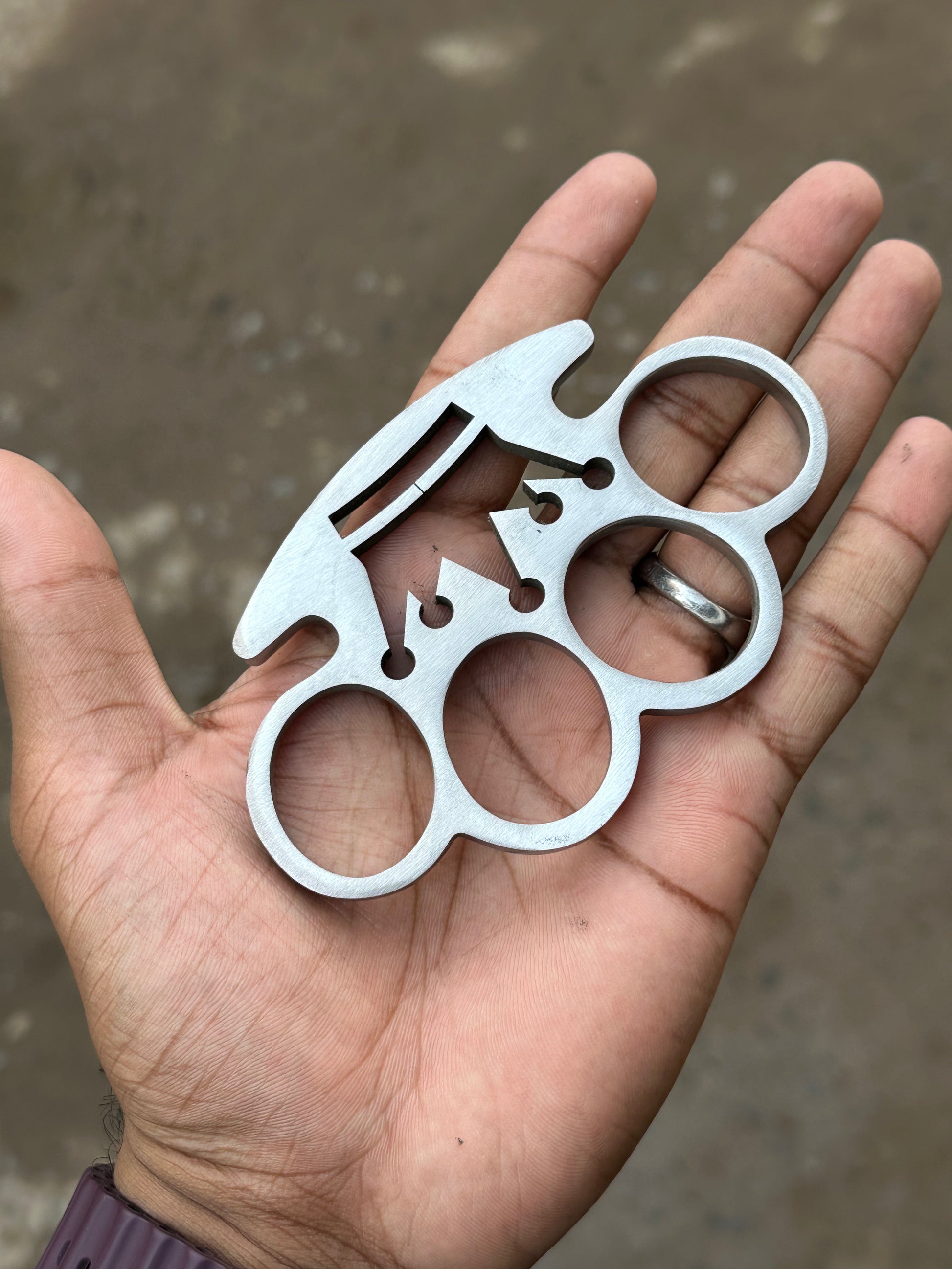 Close-up of solid stainless steel brass knuckle with leather belt loop case