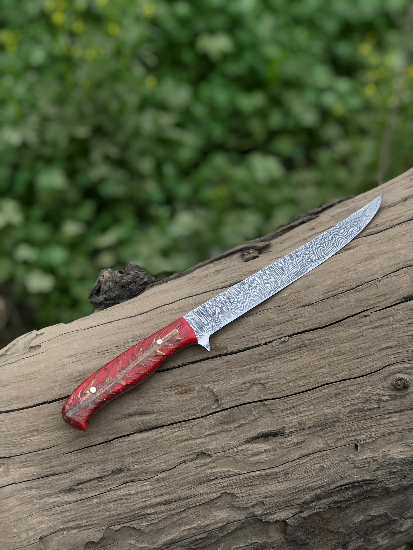 Close-up of the Damascus steel blade with twisted pattern and pine cone handle.
