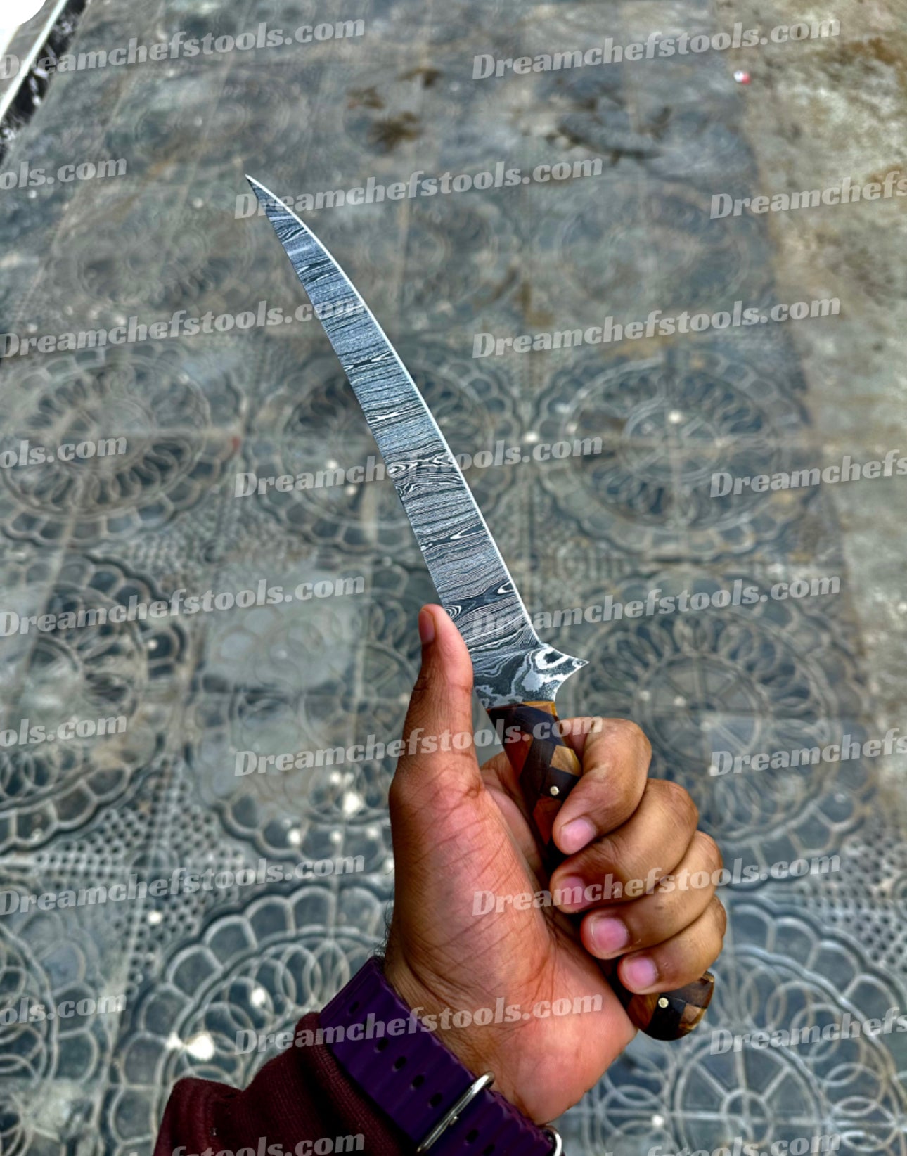 Close-up of the custom rosewood and olive wood handle on a Damascus steel fillet knife.