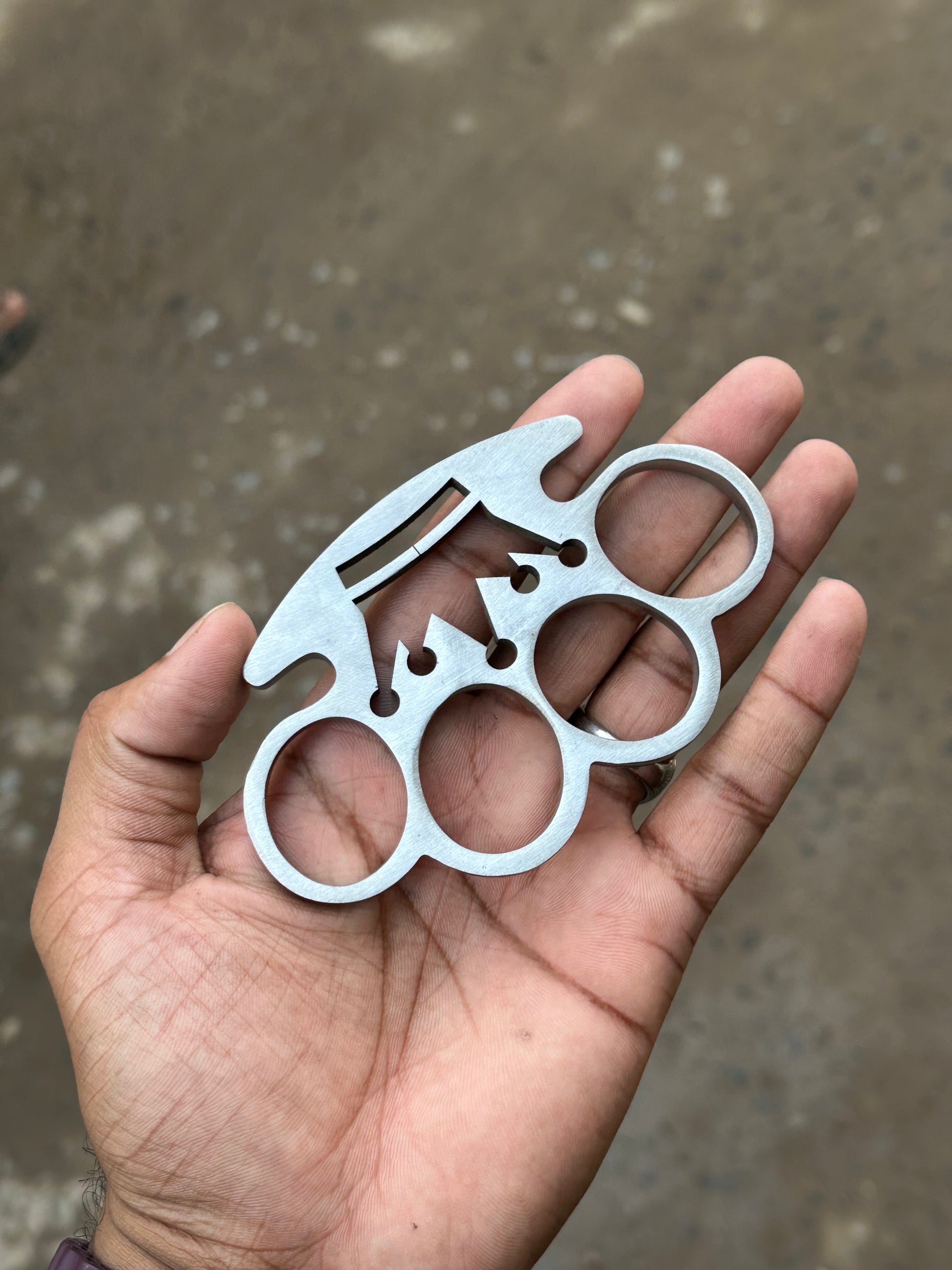 Custom brass knuckle with crown wirecut design on a wooden background