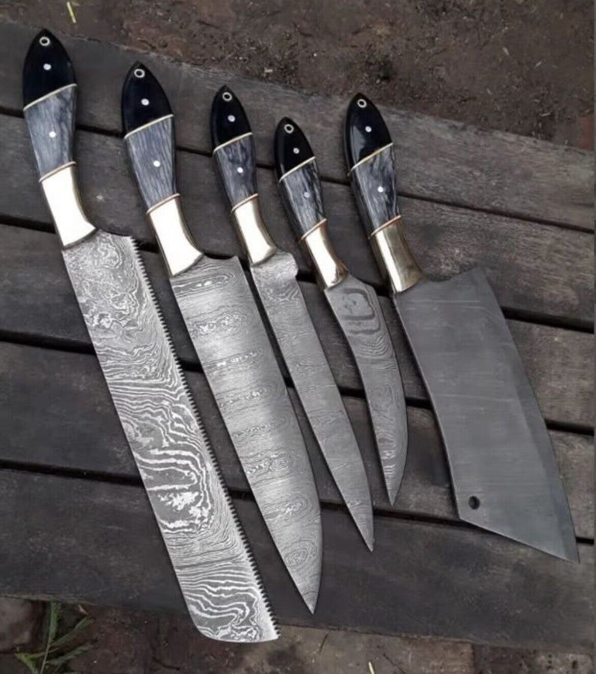 Damascus steel kitchen knives with pakkawood and buffalo horn handles, resting in a leather sheath