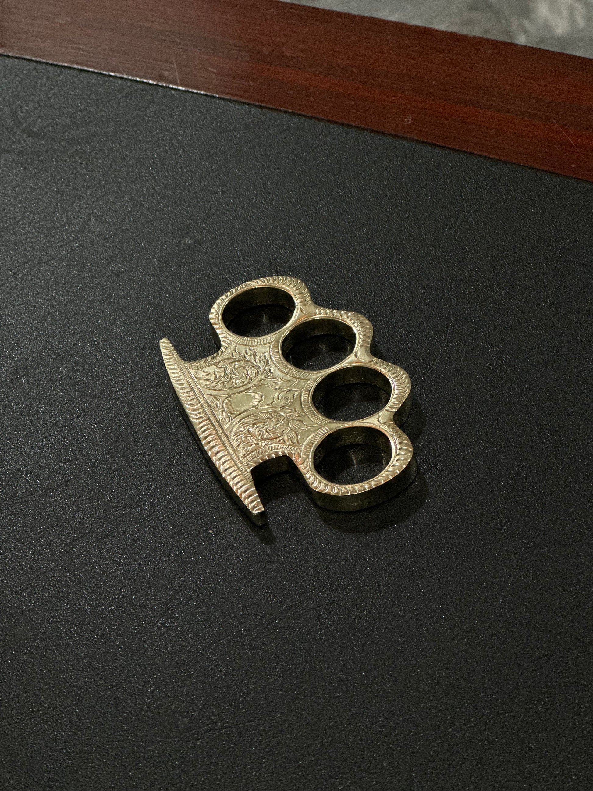 Engraved brass knuckles in a leather belt loop case for self-defense