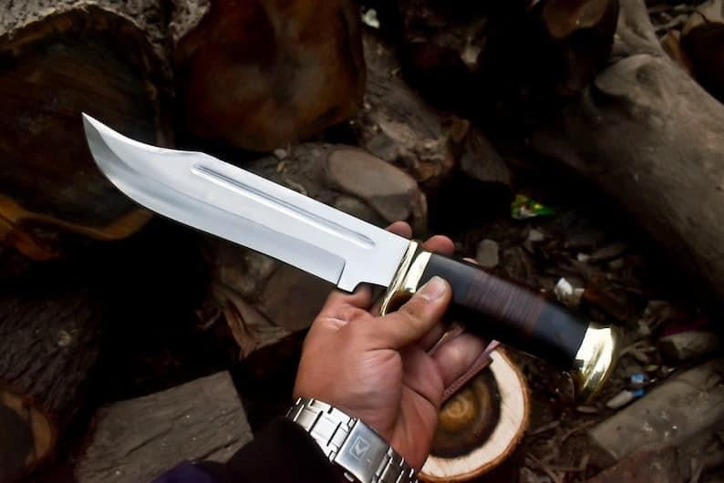 Handmade Crocodile Dundee Bowie knife with 16-inch 440C steel blade, leather and buffalo horn handle, and brass guard, accompanied by a stylish leather sheath