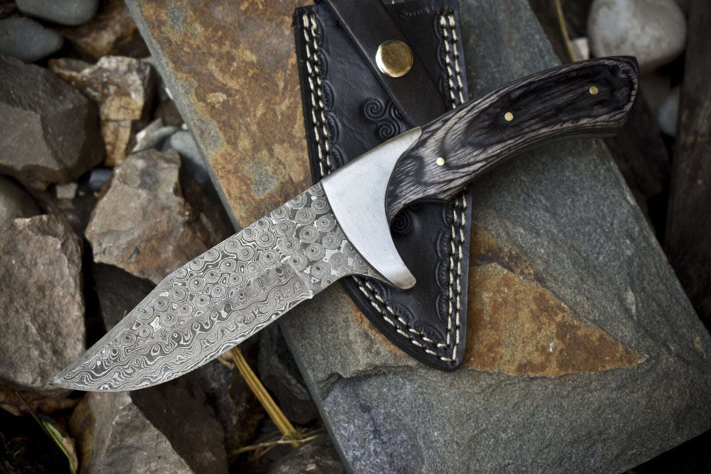 Handmade Damascus steel hunting knife with pakkawood handle and leather sheath.