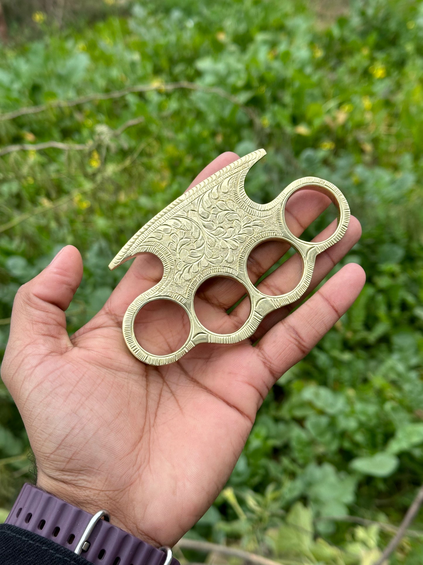 Solid brass engraved knuckle with custom design, shown with belt loop leather case