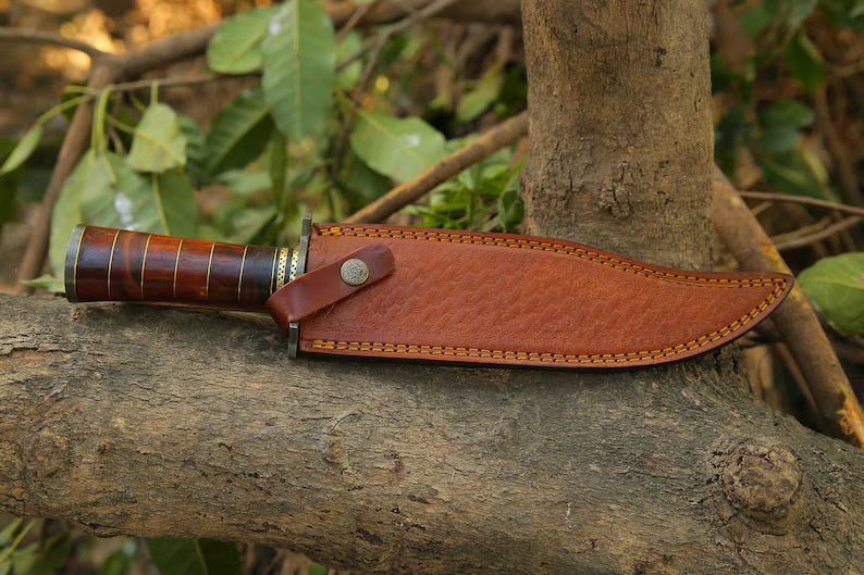 Custom handmade Damascus steel Bowie knife with a Damascus steel guard, rosewood, and brass handle, including a leather sheath.