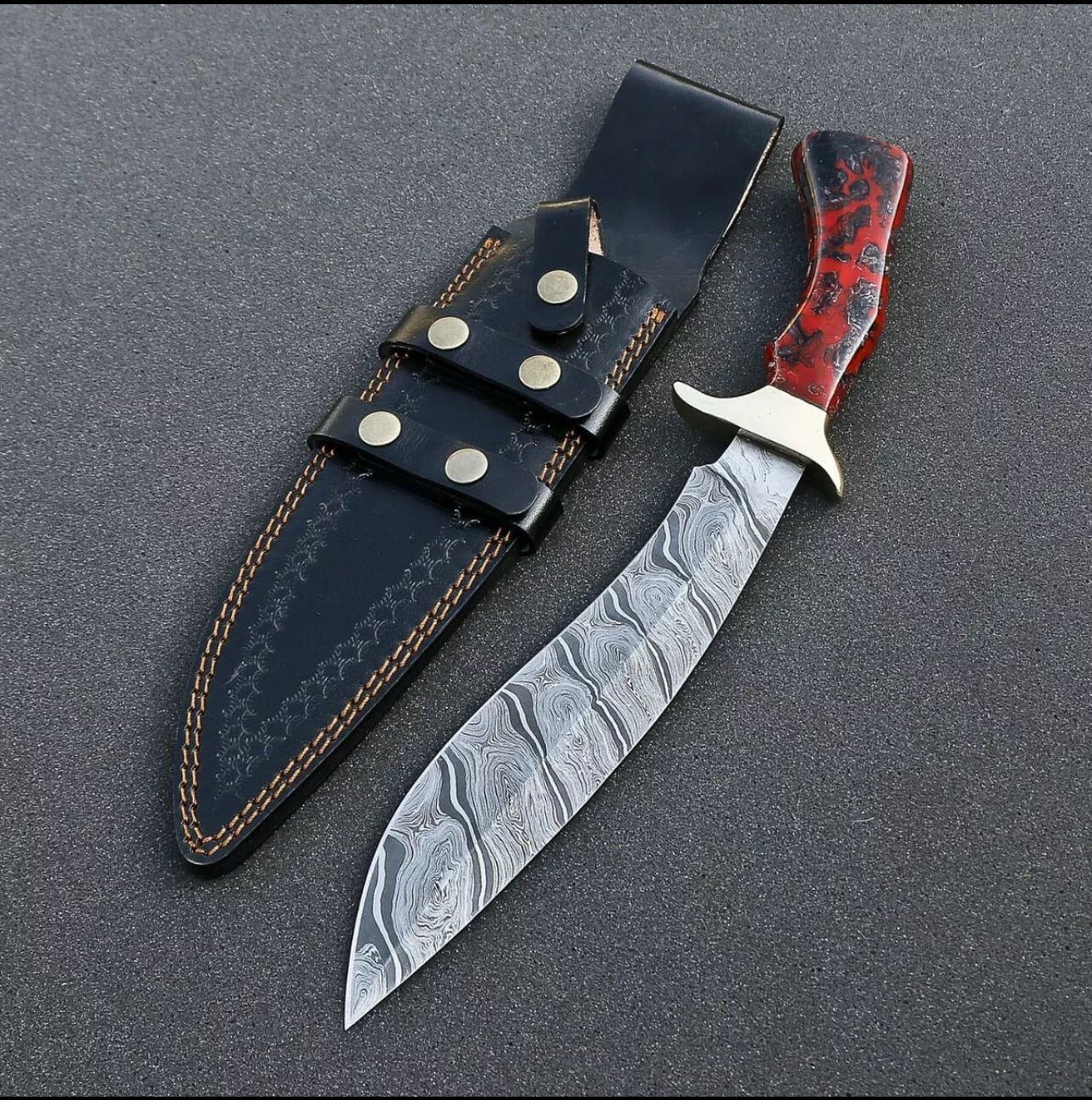 Custom handmade Damascus steel Bowie knife with a brass guard and resin handle, complete with a leather sheath.