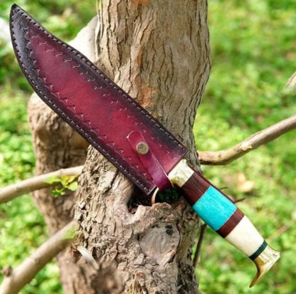 Custom handmade Damascus steel Bowie knife with a brass guard, color bone handle, and leather sheath.