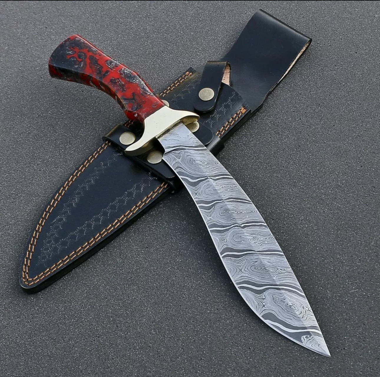 Custom handmade Damascus steel Bowie knife with a brass guard and resin handle, complete with a leather sheath.