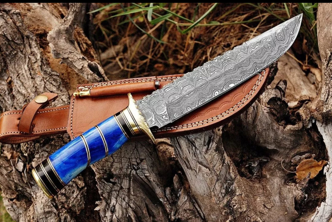 Custom handmade Damascus steel Bowie knife with a brass guard, color bone handle, and leather sheath.