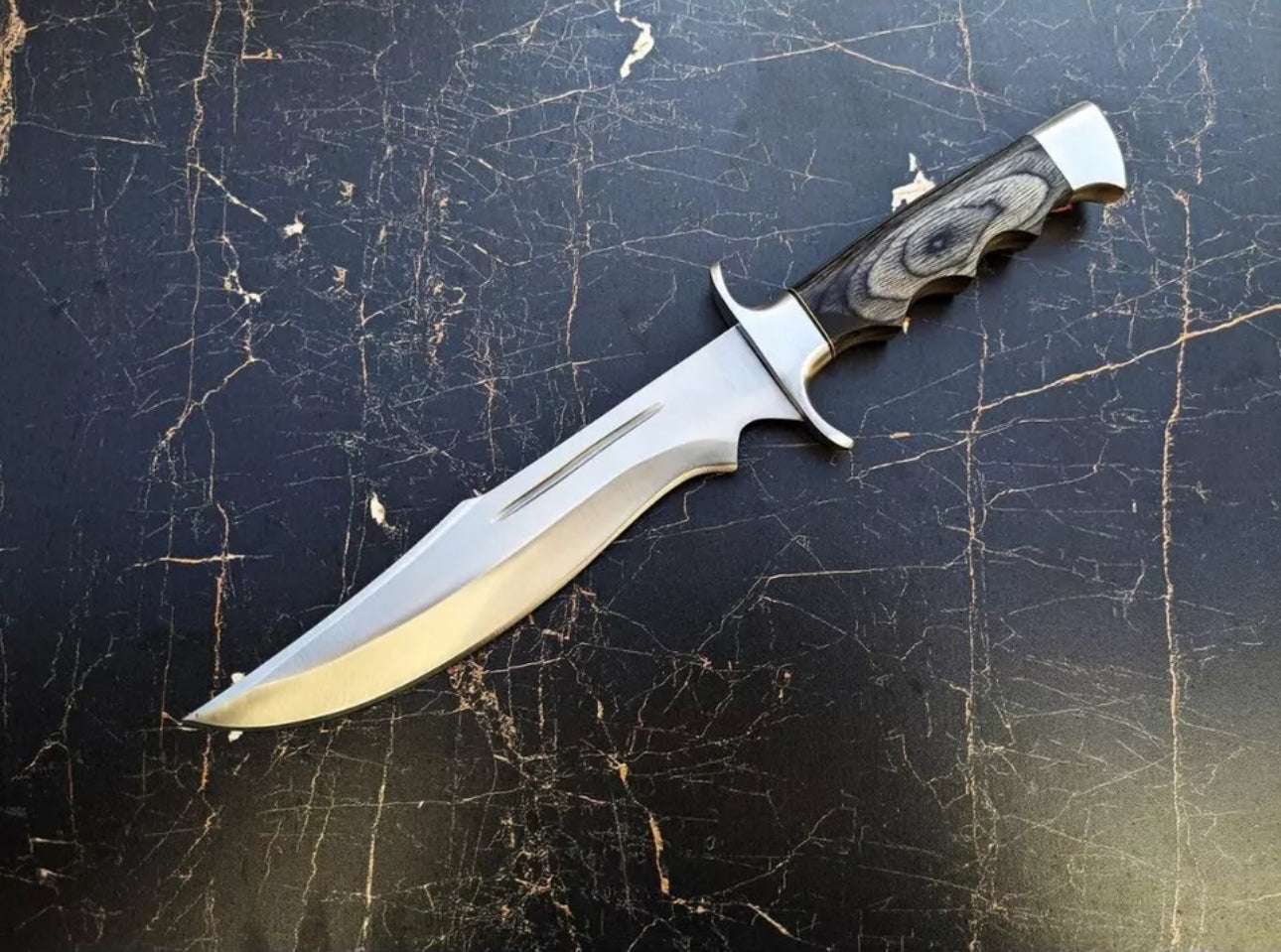 Custom handmade J2 steel Bowie knife with a steel guard, dollar handle, and leather sheath.