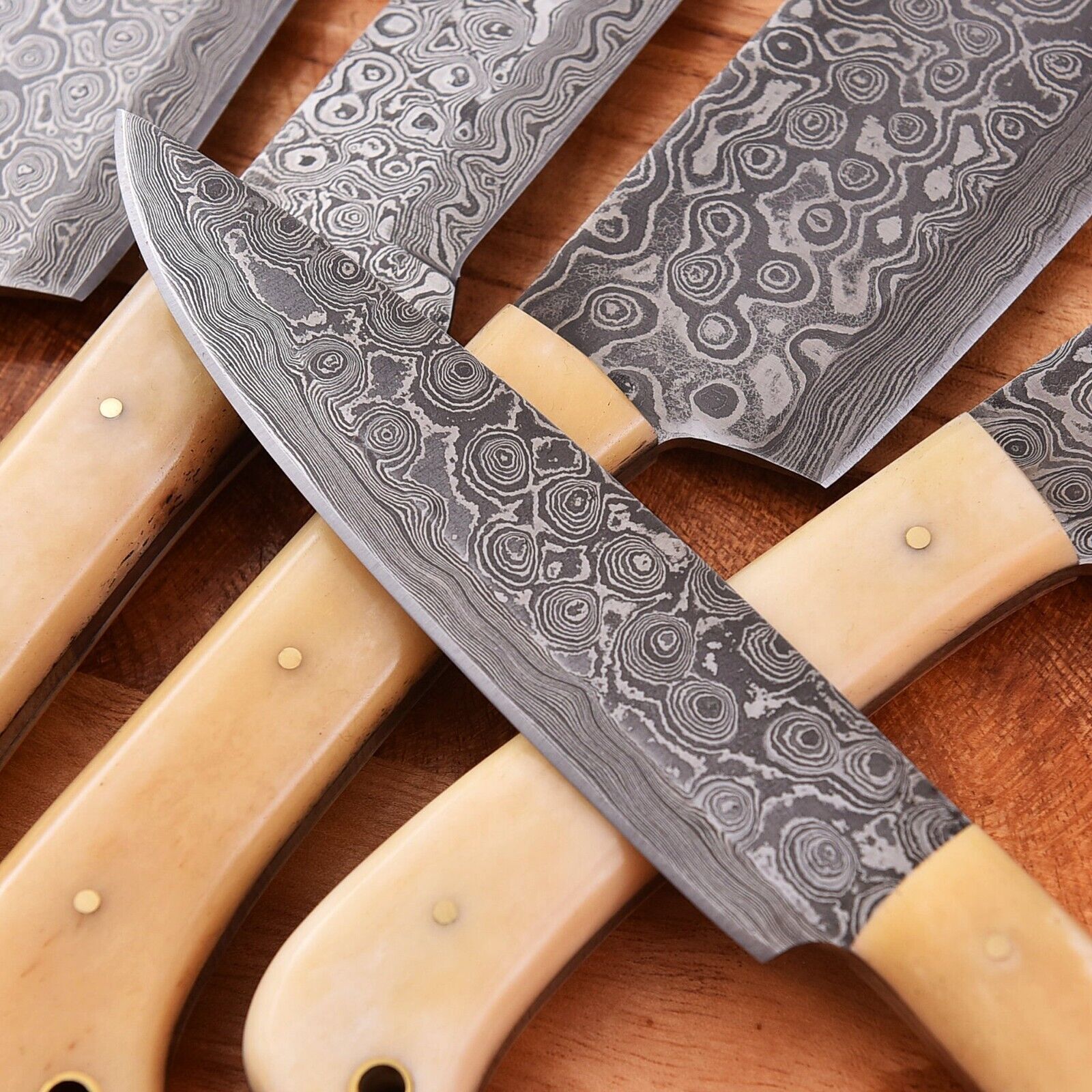 Close-up of a custom Damascus knife set with hand-forged steel blades and elegant camel bone handles, showcasing craftsmanship and precision