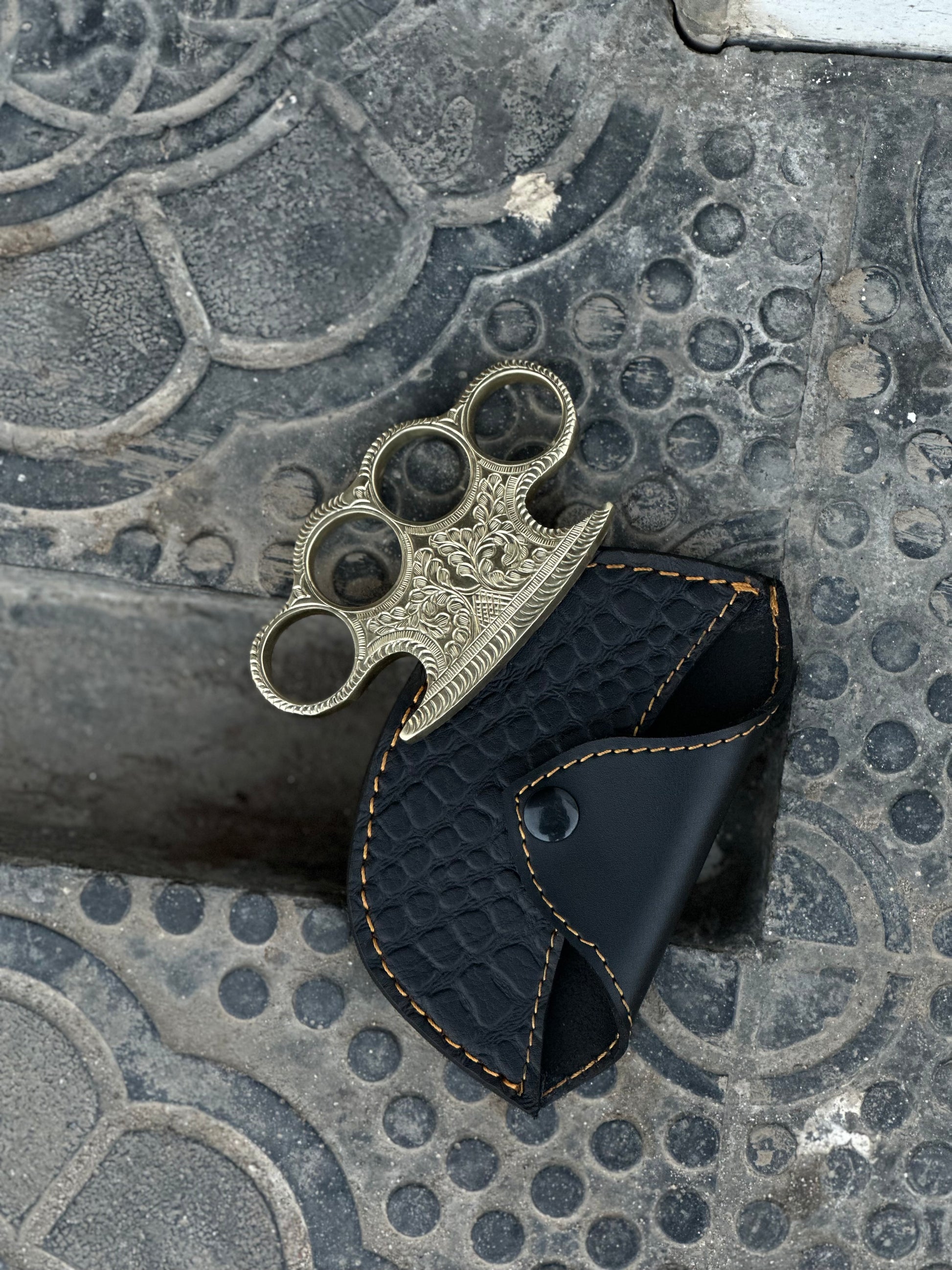 "Close-up of custom engraved brass knuckles showcasing detailed craftsmanship."
