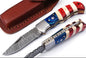 Custom Handmade Damascus folding knife with a 3-inch blade and American Flag handle, featuring a steel bolster and leather sheath