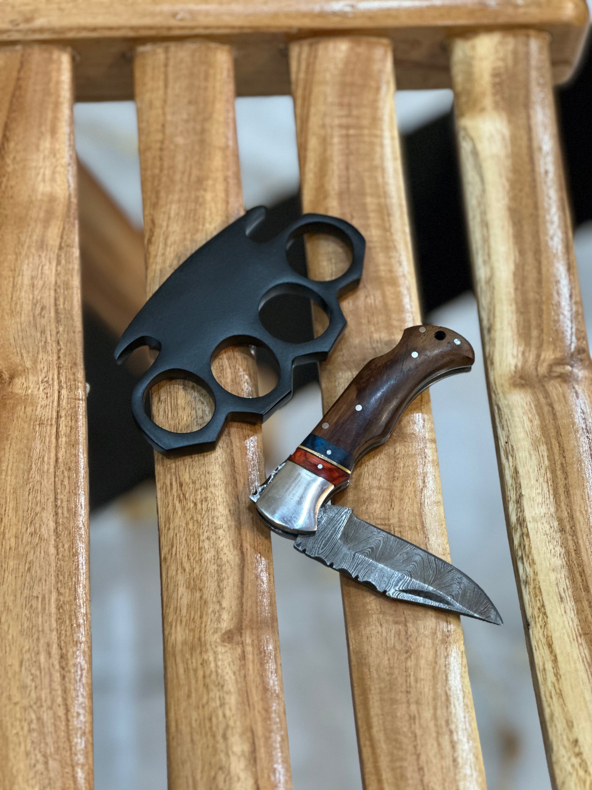 Custom handmade black steel knuckle duster with integrated pocket knife and solid brass construction in a leather case