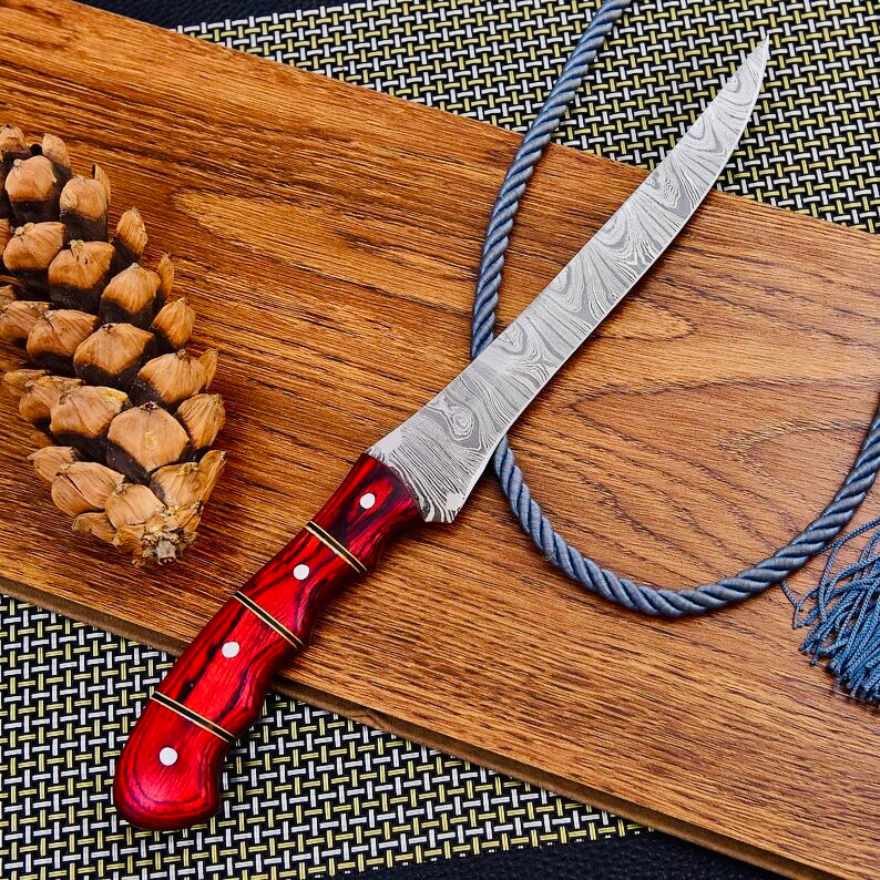 Detailed view of a custom handmade Damascus steel fishing fillet knife, featuring a 13-inch sharp edge blade, Pakka wood handle, and leather sheath