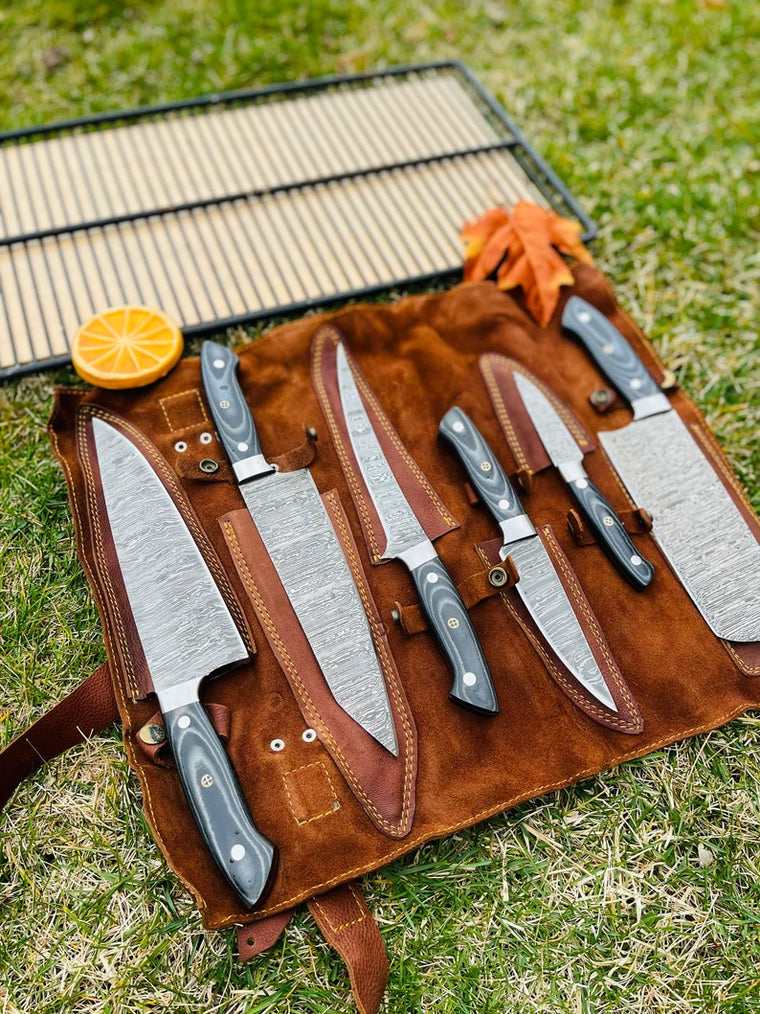 Custom handmade Damascus chef knives in G10 handles, displayed in a premium leather roll kit.
	3.	Close-up of Damascus steel blade with G10 handle from a professional 5-piece kitchen knife set