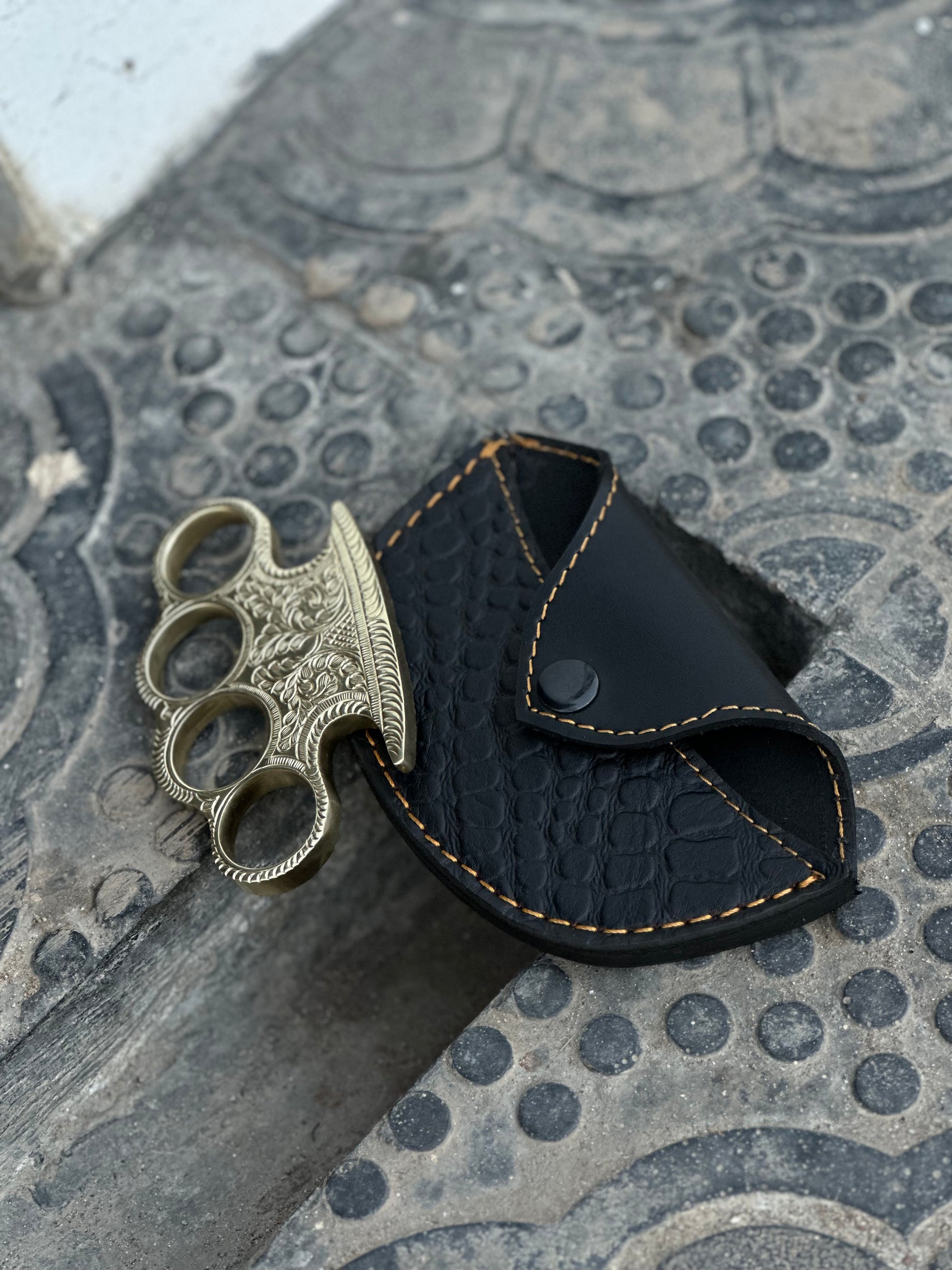 "Hand-forged pure brass knuckles with elegant engraving and leather carrying case."
