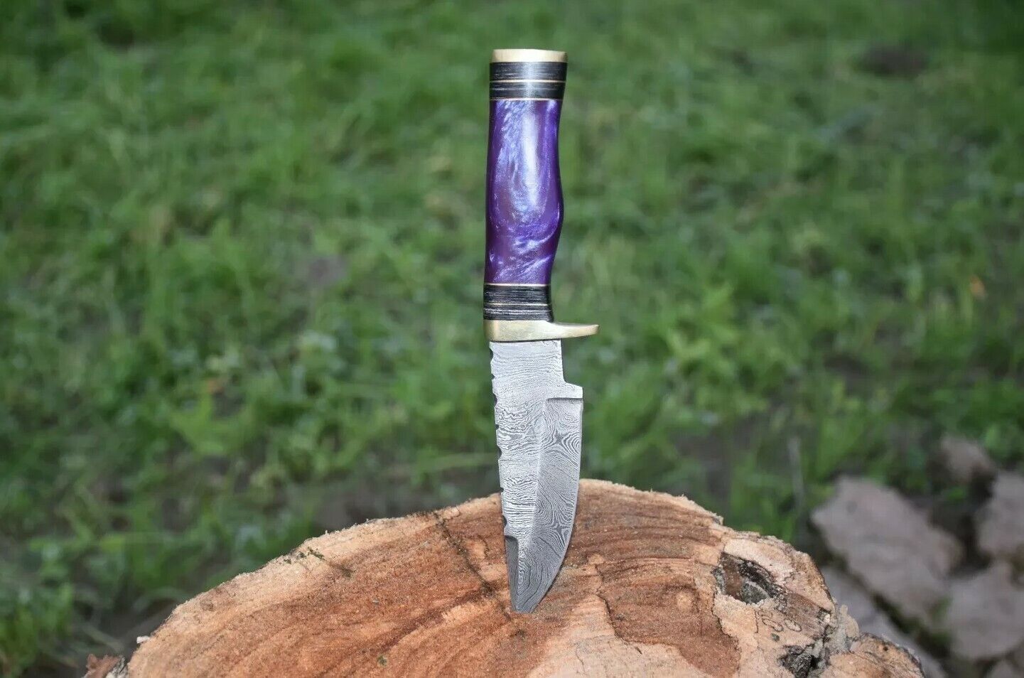 Handcrafted Damascus steel hunting knife with a polished resin handle and brass guard.