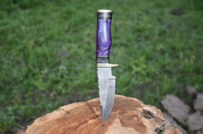 Handcrafted Damascus steel hunting knife with a polished resin handle and brass guard.