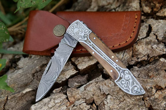 Premium Handmade Damascus Folding Knife with a 3-inch blade, rosewood handle, and steel bolster, shown in an open position with a leather sheath beside it