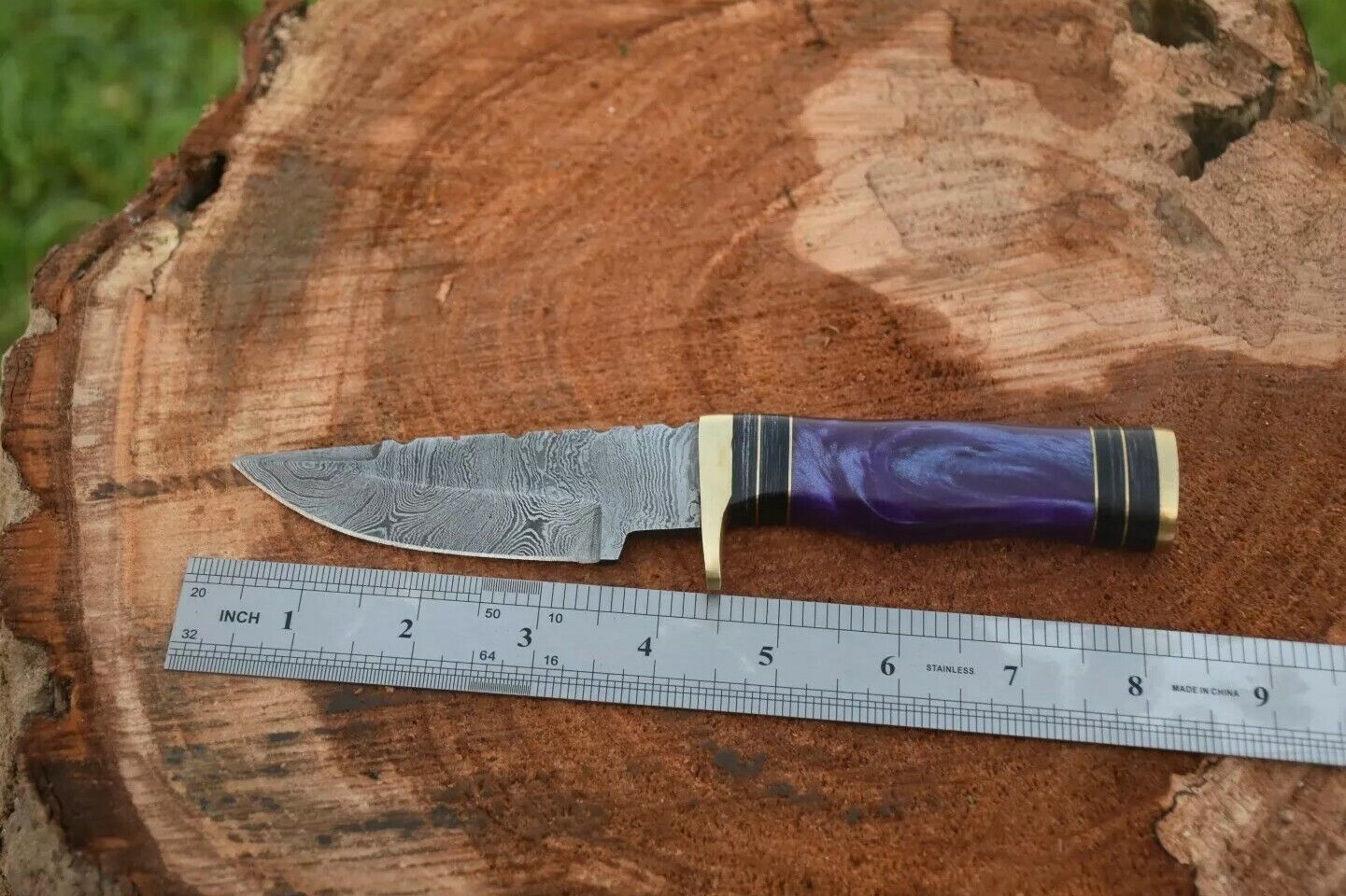Resin handle with brass guard on a custom Damascus steel hunting knife.
