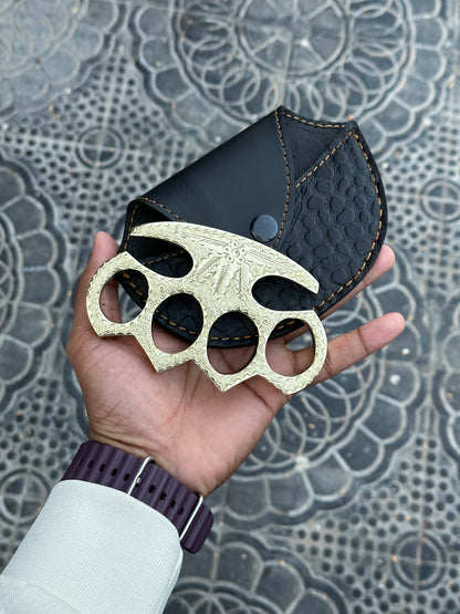 Self-defense brass knuckles with intricate engravings and a protective leather case