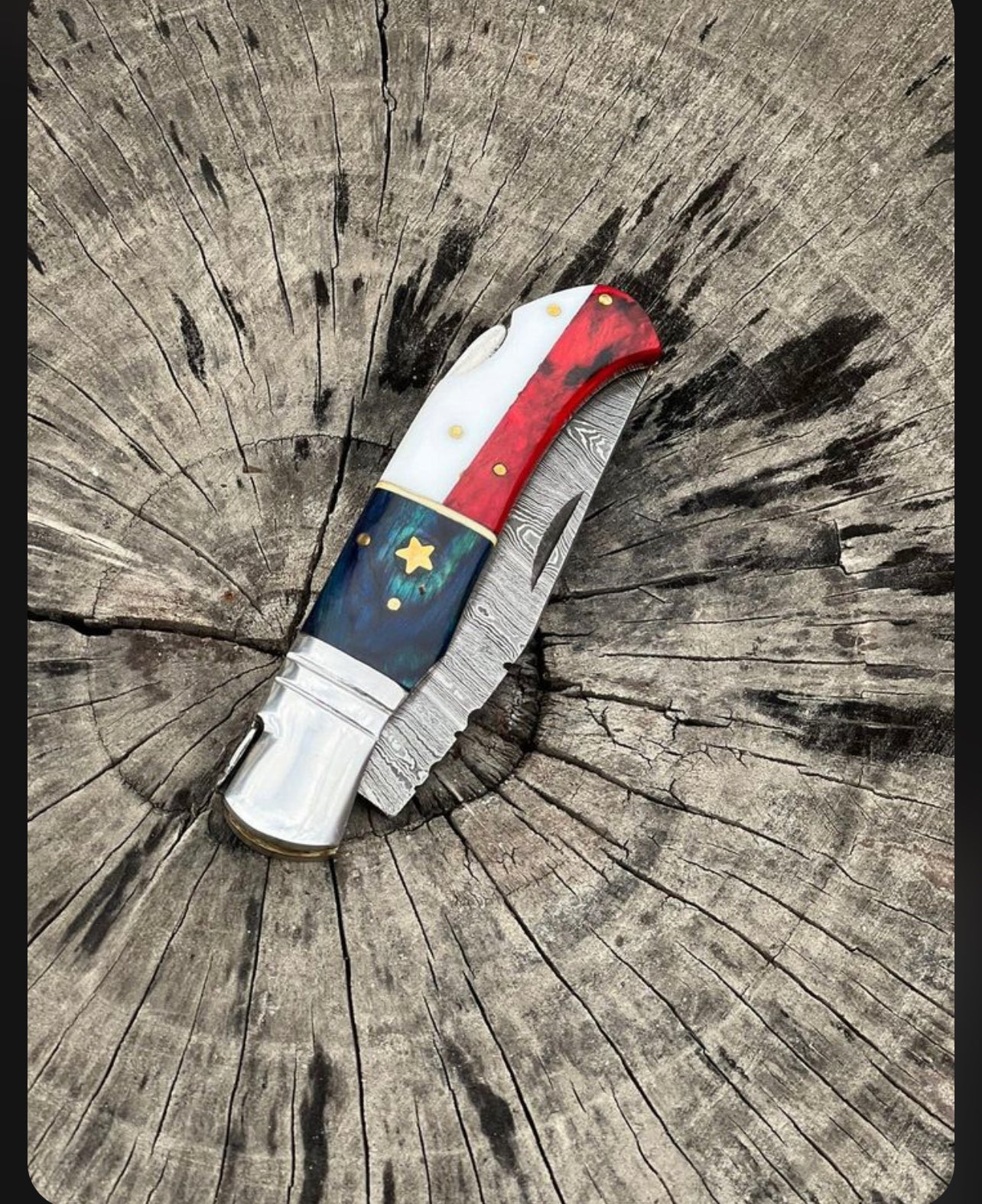 Handcrafted Damascus folding knife with a patriotic American flag handle, 3-inch blade, and steel bolster, shown with leather sheath